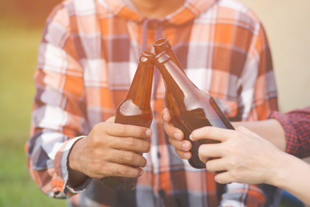 香槟旅行三个年轻的朋友在一起玩 在远足营地放松和喝啤酒干杯瓶节日啤酒饮料