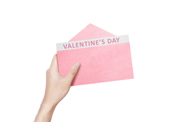 日子人的手拿着打开的粉红色信封 白色的墙上隔离着情人节的文字信封信息文本
