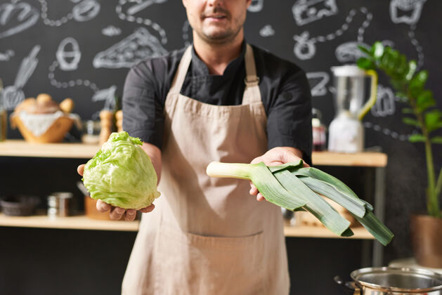 健康饮食围裙里厨师站在厨房里展示他手中新鲜蔬菜的特写镜头室内欢呼家庭厨房