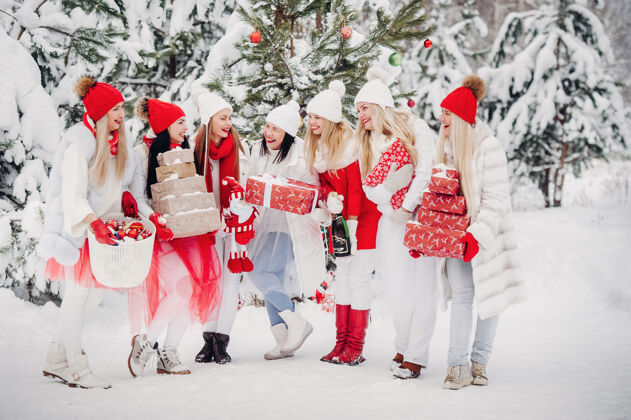 衣服一大群手里拿着圣诞礼物的女孩站在冬天森林女孩穿着红白相间的衣服 带着圣诞礼物在雪林里手套霜冻大量的雪
