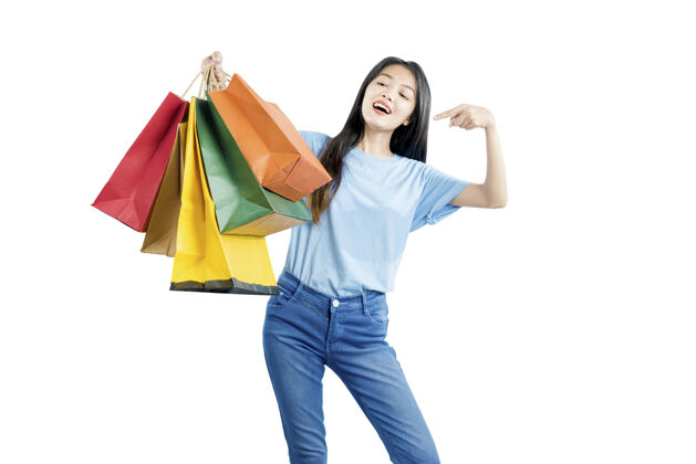 购物亚洲女人拎着购物袋隔着白墙微笑年轻泰国