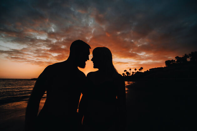 男人一对浪漫的情侣在沙滩上 背景是五颜六色的夕阳一个男孩和一个女孩在特内里费岛的夕阳下一起情人浪漫