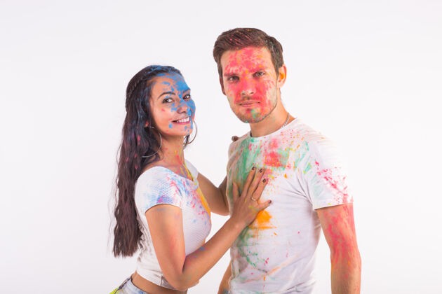 明亮友谊 爱情 胡里节 人的概念-年轻夫妇在白色的胡里节上玩色彩家伙文化多彩