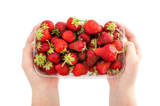 浆果两只手拿着一个白色表面上有草莓的塑料托盘草莓食物水果