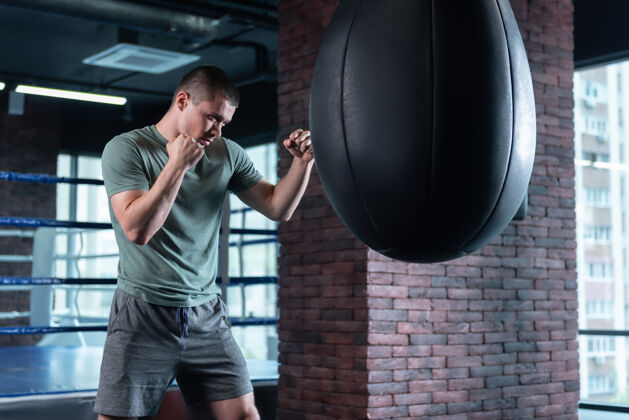 动机专业拳击手在训练时感觉很有动力 站在黑色的大拳击袋旁努力训练硬爱好课