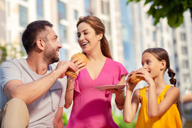 在一起美味的食物快乐的家庭一边享受野餐 一边吃着美味的汉堡包护理女儿男性