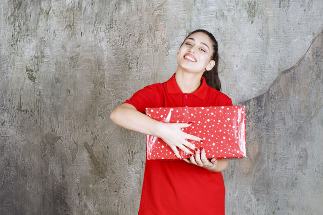 惊喜一个十几岁的女孩手里拿着一个有白点的红色礼盒晋升女人休闲