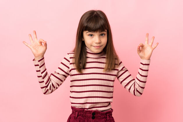 年轻小女孩被隔离在粉红色的墙上 摆出禅意的姿势模特健康运动
