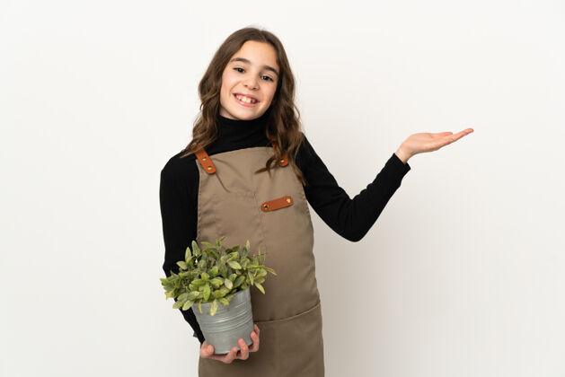 自然小女孩抱着一株隔离在白墙上的植物 向旁边伸出双手 欢迎前来花可爱手