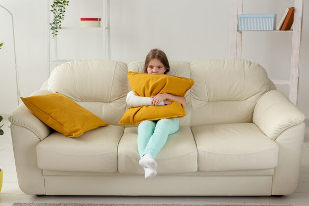 漂亮手腕或手臂骨折的孩子坐在沙发上恢复和疾病概念疾病衣服人类