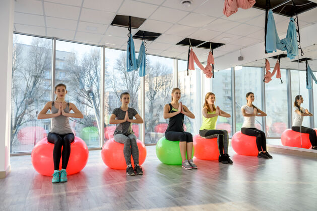 身体一群女人在健身房做球上的练习力量女子健身