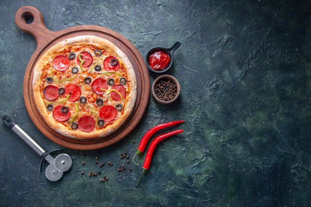 晚餐自制的比萨饼放在木制的砧板上 胡椒番茄酱放在单独的深色表面上晚餐午餐对