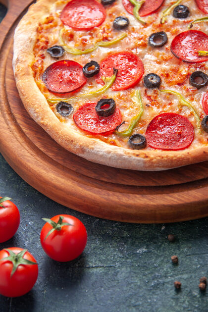 橄榄自制的比萨饼放在木制砧板上 西红柿放在孤立的黑暗表面上食物小吃奶酪