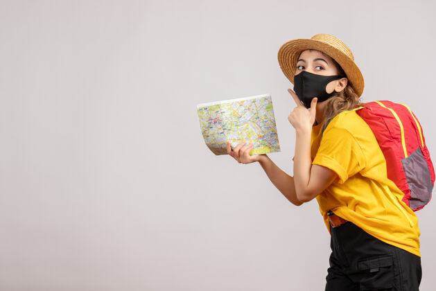 持有前视图：背着背包的年轻女子举着地图 手放在下巴上下巴灰色背包