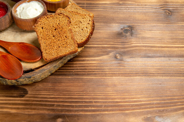 调味品正面视图不同的调味品与面包面包面包在棕色空间糕点早餐容器