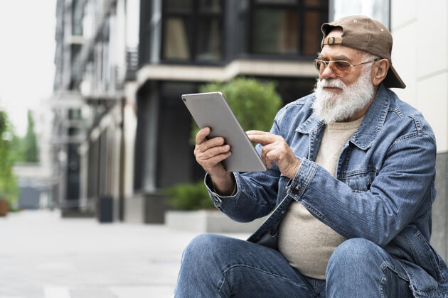 老年人在城市户外使用平板电脑的老人外面城市城市