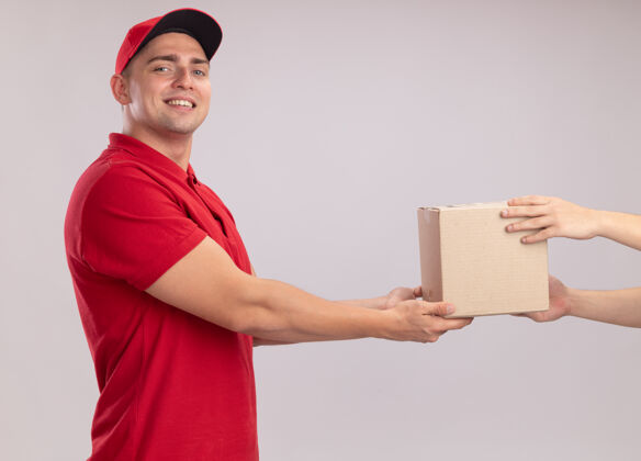 穿着面带微笑的年轻送货员穿着制服 拿着送帽盒 把客户隔离在白墙上公民年轻人客户