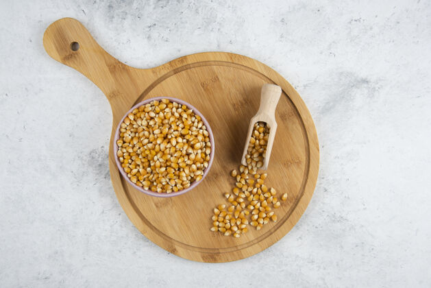 天然一碗生玉米粒 用勺子放在木板上谷类谷物堆