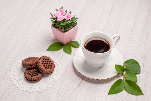 杯子前视一杯茶加饼干放在白桌子上糖茶饼干甜饼干桌子潘趣酒前面