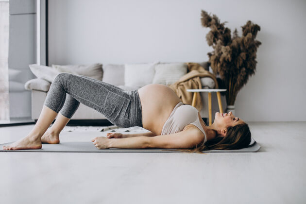 父母孕妇在家里的垫子上练习瑜伽腹部腹部运动