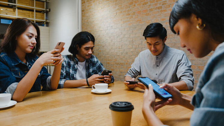 闲逛一群快乐的亚洲年轻朋友 一起坐在咖啡馆里玩得开心 一起使用智能手机网络团体年轻