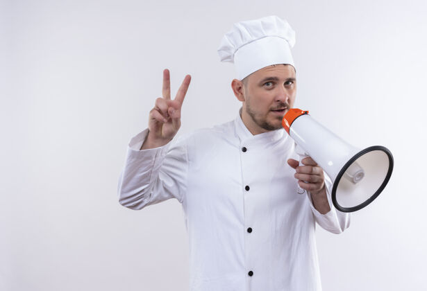 厨师自信的年轻帅哥厨师身着厨师制服 手持扬声器 做着隔离在白墙上的和平标语制服和平厨艺