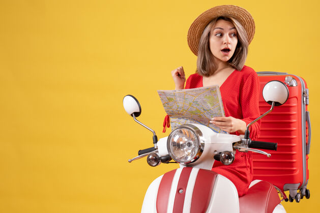 人一个戴着巴拿马帽子 骑着轻便摩托车 拿着地图的红色手提箱的漂亮女人时尚手提箱地图