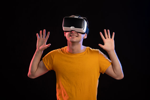 头饰戴着虚拟现实耳机的年轻人在黑暗的墙上的画像视频虚拟现实黑