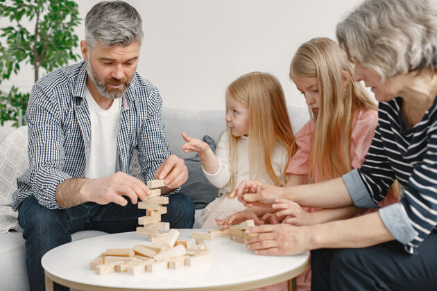 街区快乐的爷爷奶奶和孙子孙女一起玩积木塔游戏客厅内部沟通关系童年
