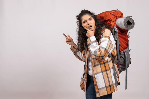 美丽正面图：年轻女子背着背包在白色背景的森林里徒步旅行度假山上航空旅游校园校园伞徒步旅行