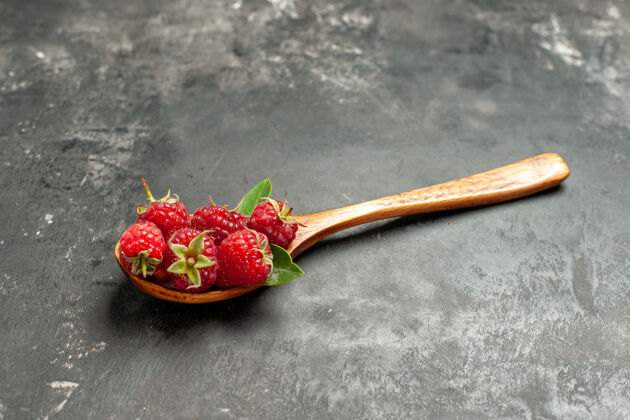 浆果正面图新鲜的红色覆盆子放在木勺上 灰色水果颜色的蔓越莓野生照片浆果甜点食物草莓