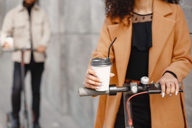 人欧洲女孩阿尼迪亚男孩骑着滑板车微笑喝咖啡的人跨种族城市流动性