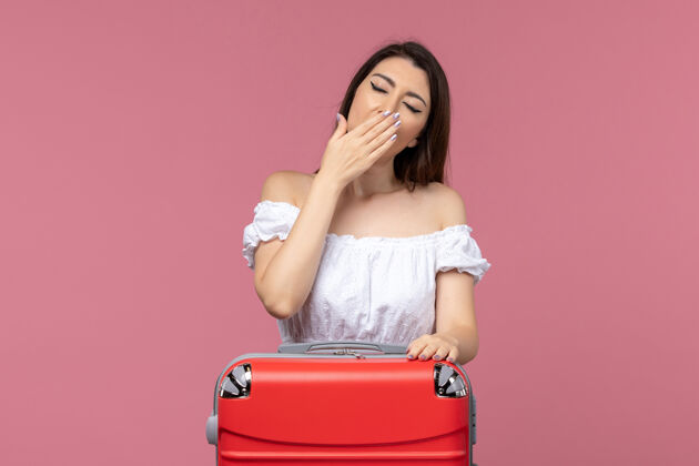旅行正面图年轻的女性准备度假与她的大袋子打呵欠粉红色背景国外海上旅行航程漂亮成人