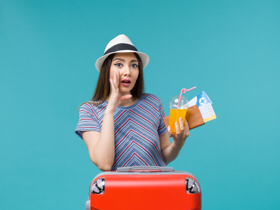 包前视图度假妇女与她的红色袋子举行的蓝色背景旅行旅行旅行度假女性旅行票和果汁微笑举行美丽