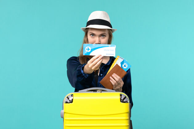 持有正面图年轻女子拿着机票 准备在蓝色背景上度假旅行航海飞机度假成人职业人