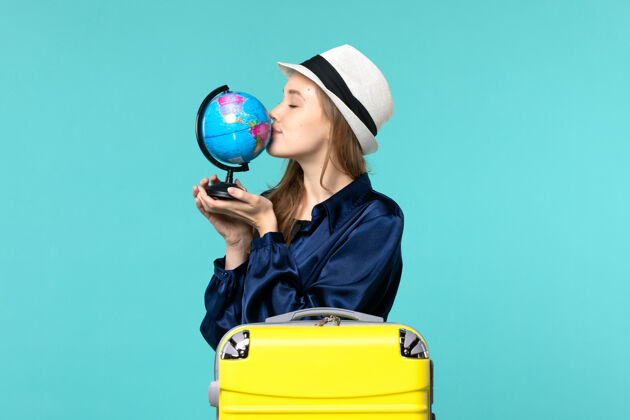 地球仪正面图年轻女子准备度假 拿着地球仪在蓝色背景飞机上亲吻它远航女子海上之旅微笑肖像成人