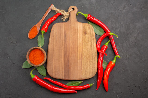 红胡椒顶视图红辣椒一个砧板架在黑桌子上留下一个木勺和一碗红辣椒粉 还有复印空间支架顶部胡椒