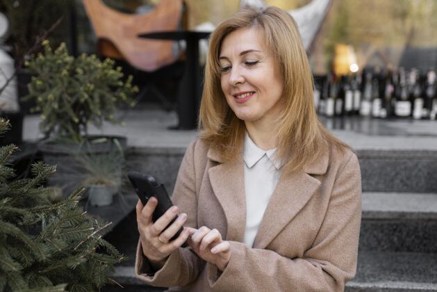 女人快乐的中年妇女正在检查她的手机积极城市生活方式