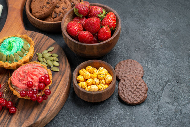 水果前视图奶油蛋糕与水果和饼干在黑暗的背景可食用水果饼干农产品