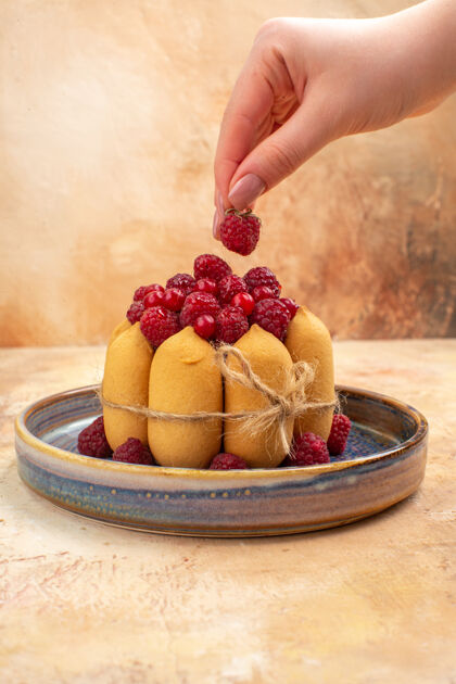 浆果手拿草莓放在新鲜出炉的水果软蛋糕上的垂直视图手美味食物