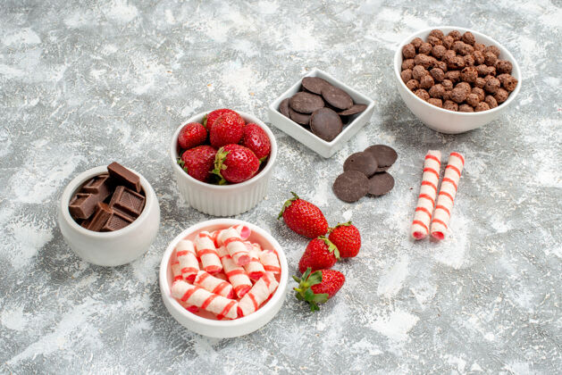 磨碎的底视图碗 灰白色背景上有糖果草莓巧克力谷类糖果和一些草莓糖果巧克力浆果巧克力食物