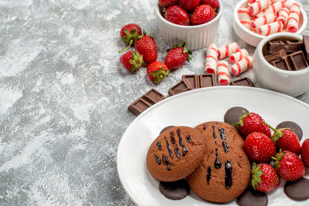 底部底部特写饼干草莓和圆形巧克力放在白色盘子上 糖果草莓巧克力碗放在灰白色的桌子上盘子巧克力水果