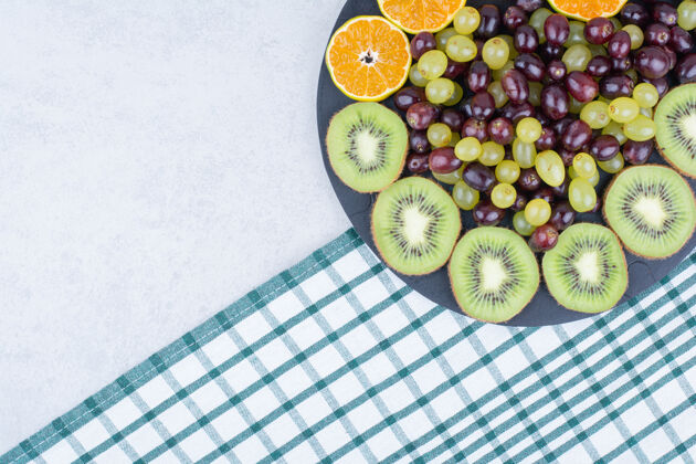 食物桌布上放满了葡萄 猕猴桃和橘子的深色盘子橙色猕猴桃水果