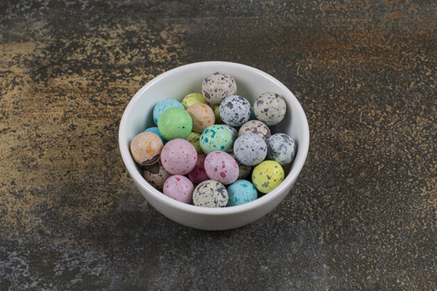 小吃一碗五颜六色的糖果放在大理石上圆巧克力石头