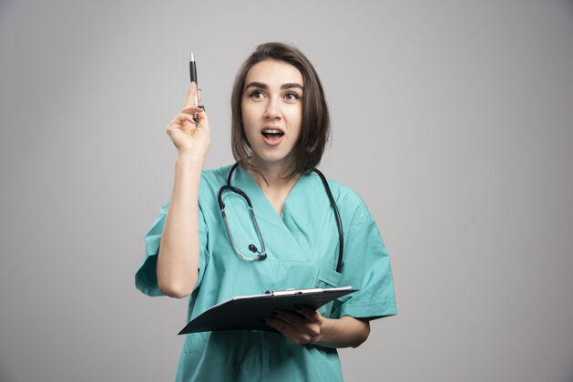 妇女女医生指着灰色背景上的东西高质量的照片医疗工作肖像