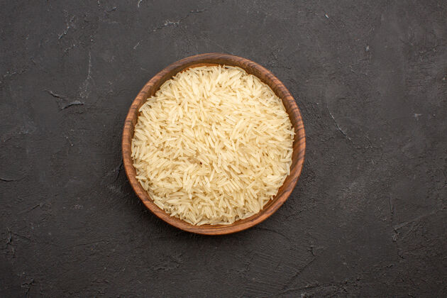 生的在灰色表面的棕色盘子里的生大米的顶视图早餐面团营养