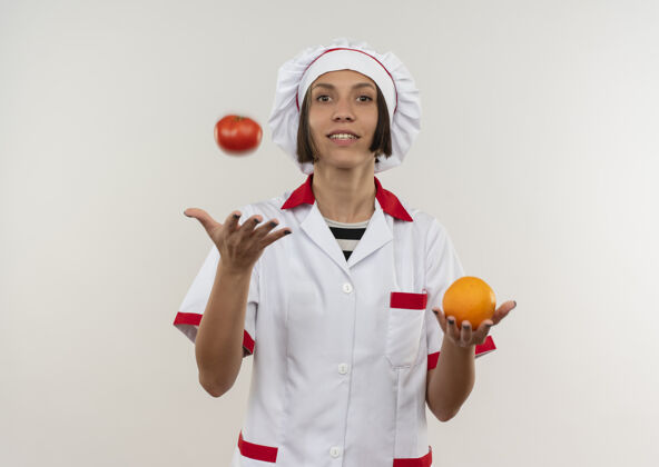 感觉身着厨师制服的年轻女厨师面带微笑 手里拿着橘子 把隔离在白墙上的西红柿扔了起来西红柿衣服人