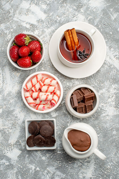 巧克力灰白色的桌子上有可可糖果草莓巧克力茶肉桂的顶视图碗蛋糕草莓早餐