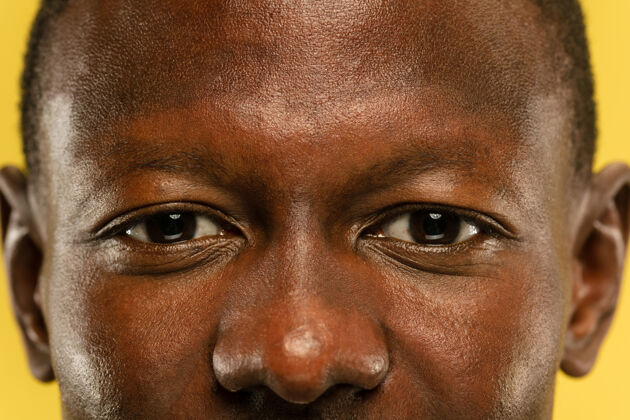 商人黄色摄影棚背景上的非洲裔美国年轻人的特写肖像皮肤保养良好的漂亮男模人类情感的概念 面部表情 销售 广告眼睛和脸颊男性手手势