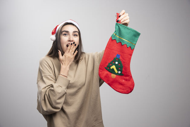 女孩惊异的年轻女孩手拿圣诞袜 看起来很惊讶张开礼物嘴巴